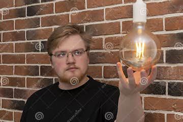 A Bearded Man with a Light Bulb on Against a Brick Wall. Concept: Connection and Disconnection ...