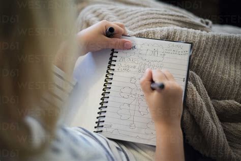 High angle view of girl writing in diary while sitting at home stock photo