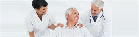 Happy senior patient with doctors sitting in wheelchair at the hospital ...