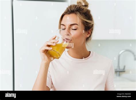 Woman drinking freshly squeezed homemade orange juice in white kitchen Stock Photo - Alamy