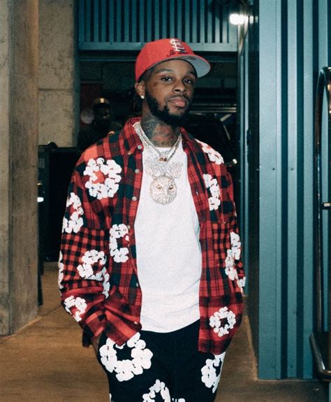 a young man wearing a red and black flannel jacket with flowers on it