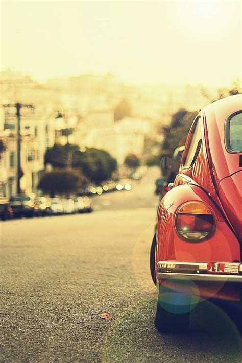 an old red car is parked on the street