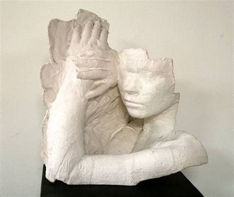 a white sculpture with hands covering it's face