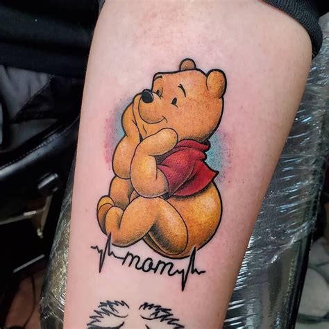 a winnie the pooh tattoo is on someone's left arm and it says, mama