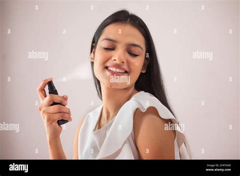 A HAPPY YOUNG WOMAN SPRAYING ROSE WATER Stock Photo - Alamy
