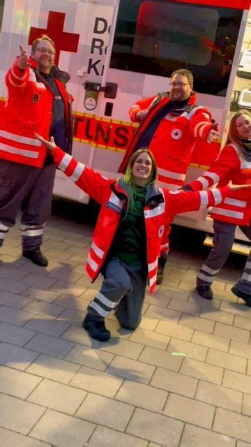 a group of people standing in front of a fire truck with their arms up and hands out