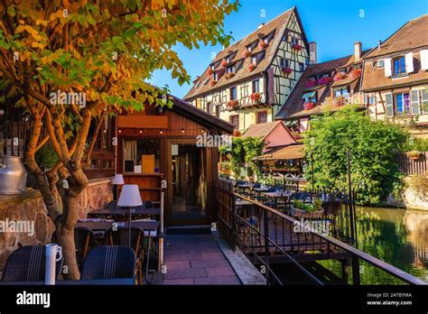 Restaurant terrace with tables located on canal bank in Colmar village ...