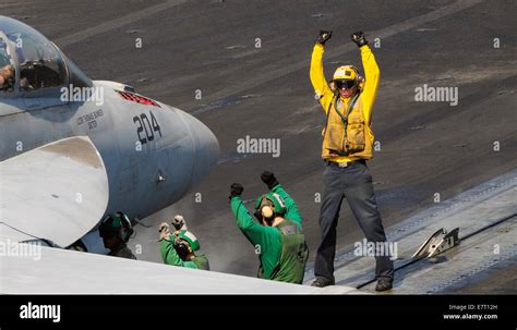 A US Navy sailor on the flight deck crew directs a F/A-18F Super Hornet ...