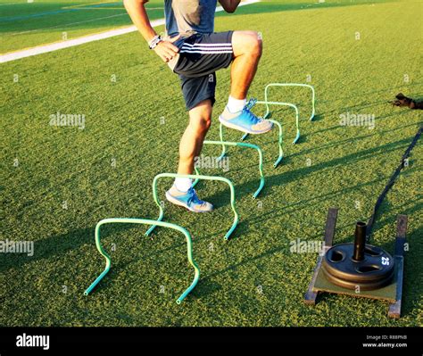 An athlete gets some agility training done by running over mini hurdles ...