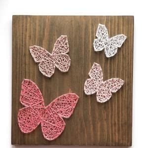 four pink and white crocheted butterflies on a wooden board