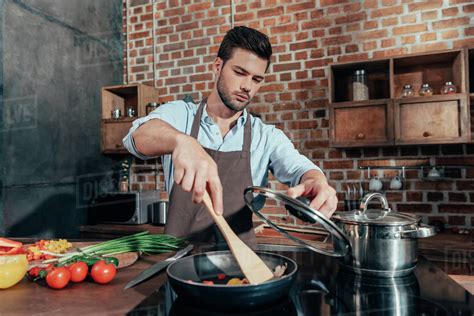 Pensive handsome man with apron cooking - Stock Photo - Dissolve