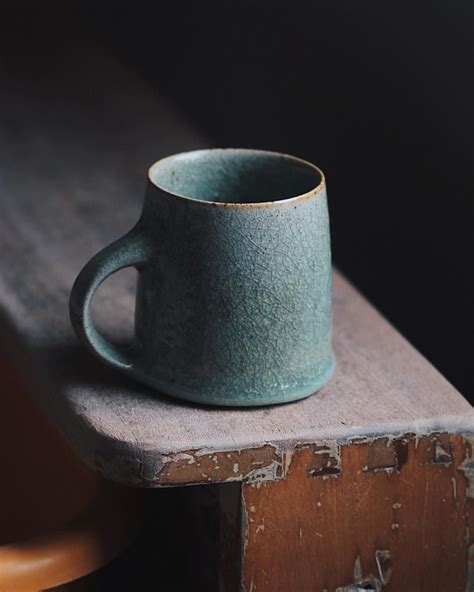 A thickly glazed dark green mug, thinly thrown and fired in a reduction ...