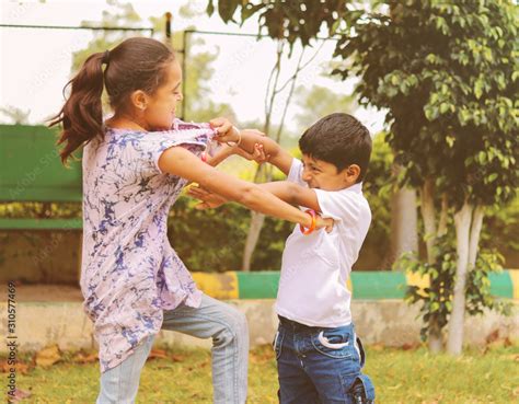 Two little siblings fighting with each other at park - Kids hitting and pulling dress due to ...