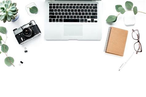 an open laptop computer sitting on top of a desk next to a camera and plant