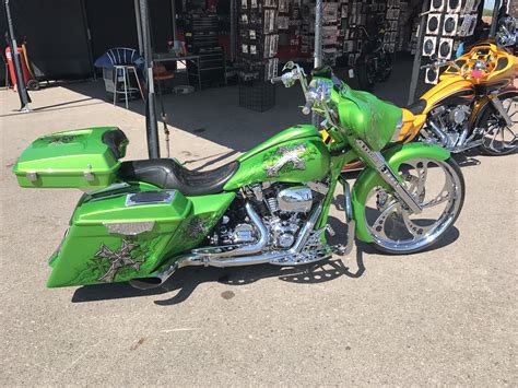 a green motorcycle parked in front of a building next to another bike on the street