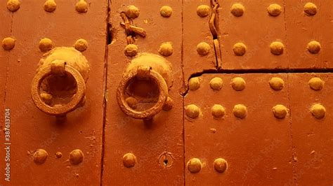 old wooden studded double doors in golden brown paint in Marrakesh Morocco, with original ...