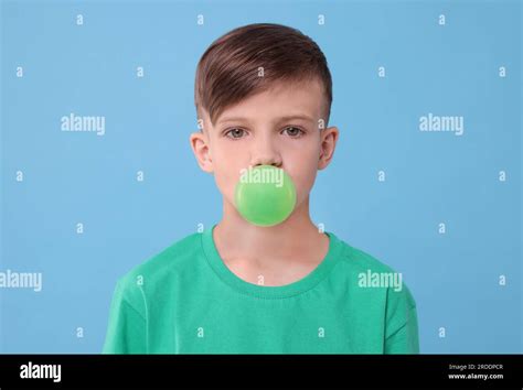 Boy blowing bubble gum on light blue background Stock Photo - Alamy