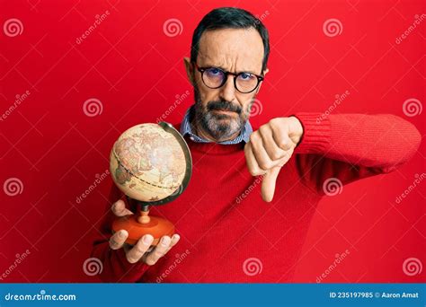 Middle Age Hispanic Man Holding Vintage World Ball with Angry Face, Negative Sign Showing ...