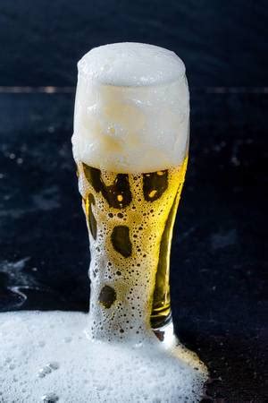 A glass in a man's hand against the background of the television screen ...