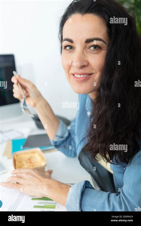 businesswoman eating at office desk Stock Photo - Alamy