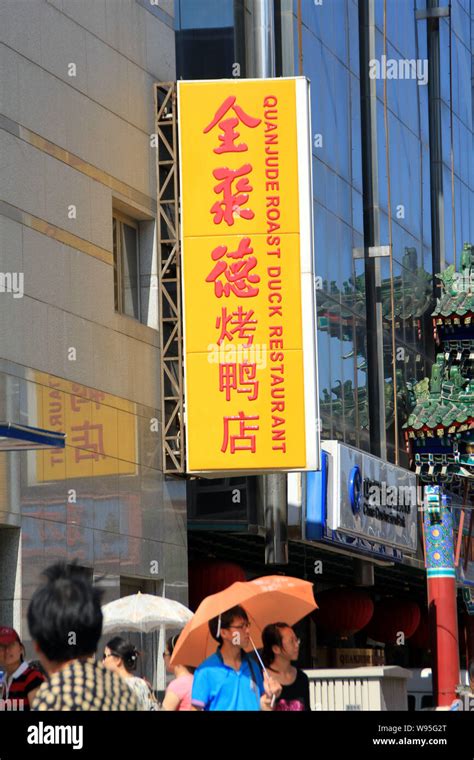 --FILE--Pedestrians walk past a Quanjude roast duck restaurant in ...