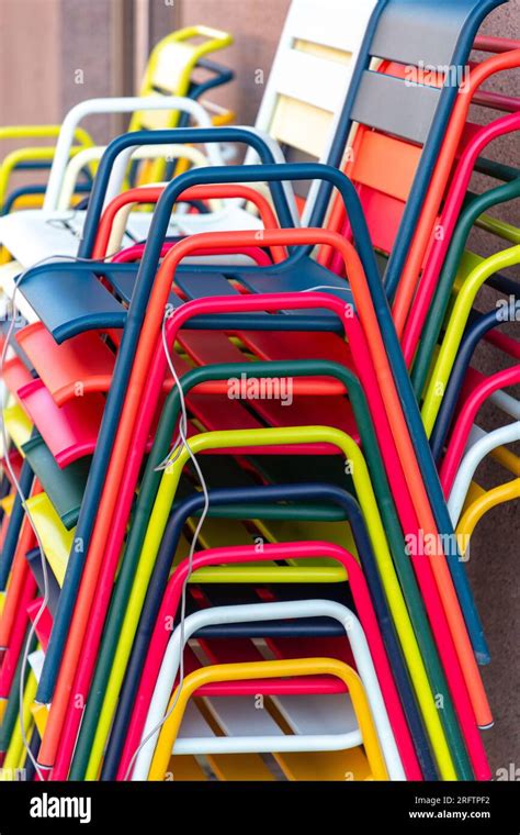 Stacked colorful metal chairs, vertically organized modern chairs Stock Photo - Alamy
