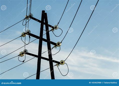 A Rusty Black Power Line with Bright Glass Insulators on the Blue Sky with White Clouds ...