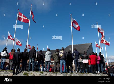 Danish and Greenland flags above people waiting to glimpse the Danish Royal Family, National Day ...