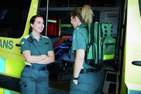 Smiling female paramedics talking while standing by ambulance in parking lot - Stock Photo ...