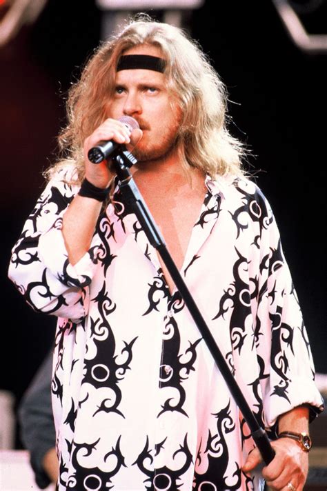 an image of a man that is on stage with a microphone in his hand and wearing a bandana