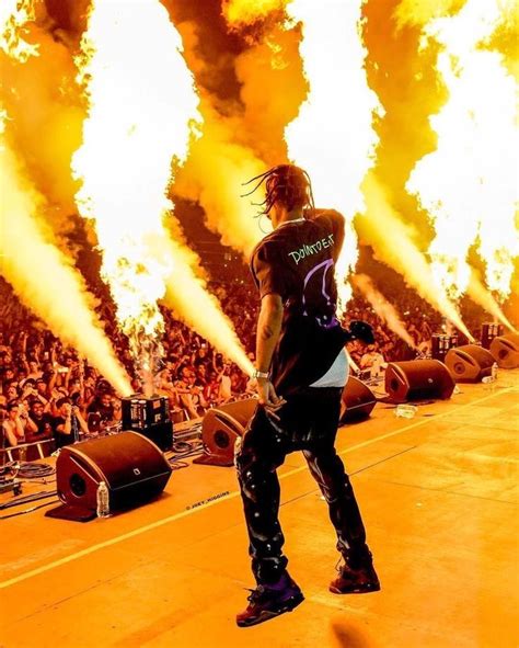 a man standing on top of a stage in front of a large crowd with fire