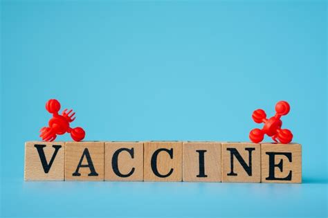 Premium Photo | Red virus with wooden cubes with words ''vaccine" on blue background.