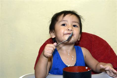 One 1 Year Old Asian Baby Boy Learning To Eat by Himself by Spoon, Messy on Baby Dining Chair ...