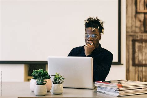 «Young Black Man Working On Laptop In Bright Minimalist Office» del colaborador de Stocksy ...