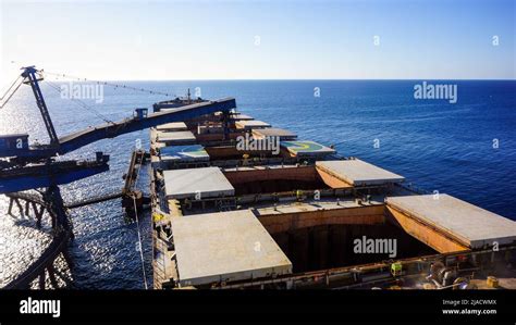 Bulk carrier ship loading operation. All cargo holds open for loading Stock Photo - Alamy