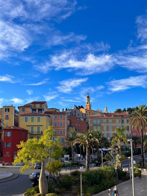 people are walking on the sidewalk in front of some buildings and palm trees with a blue sky