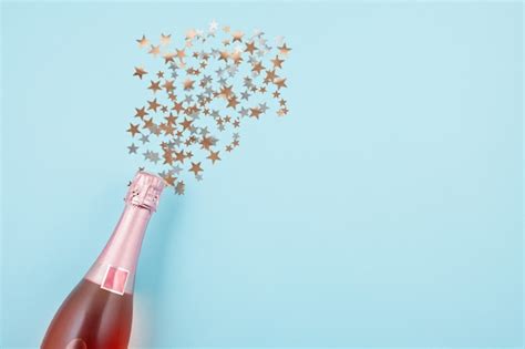 Premium Photo | Champagne bottle with confetti on blue background