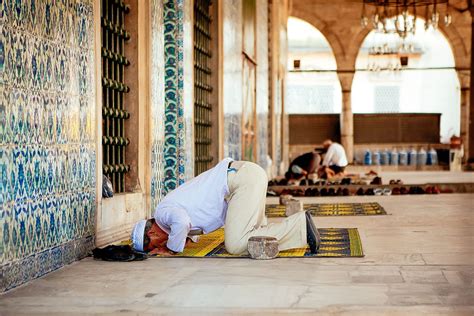 a man kneeling down on the ground in front of a wall covered with ...