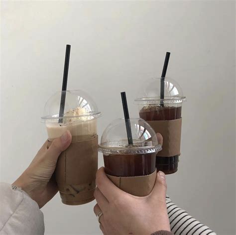 three people holding up cups with drinks in them and straws sticking out of the lids