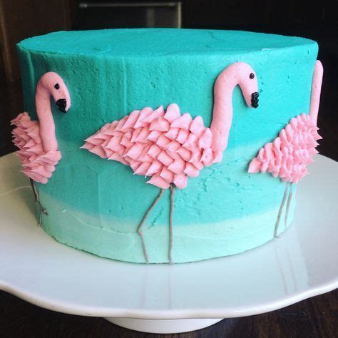a cake decorated with pink and blue frosting flamingos on a white platter