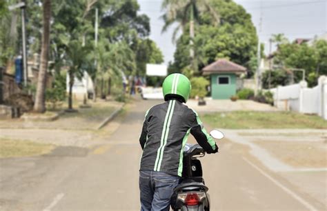 Premium Photo | Rear view of motorcycle taxi driver pushing his motorcycle