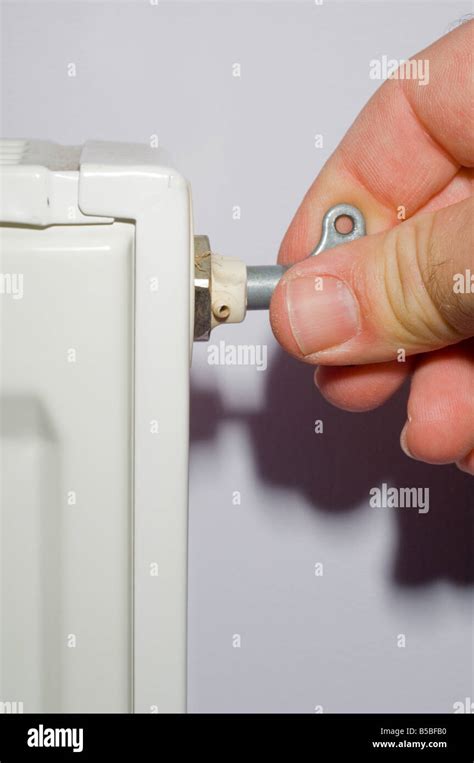 Image showing person bleeding a radiator with rad key to remove air from heating system to ...