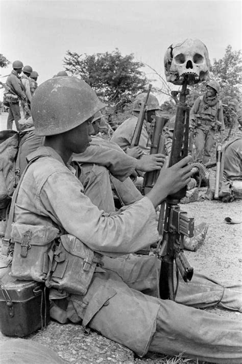 A child soldier with a human skull resting on the tip of his rifle. Dei Kraham Cambodia. 1973 ...