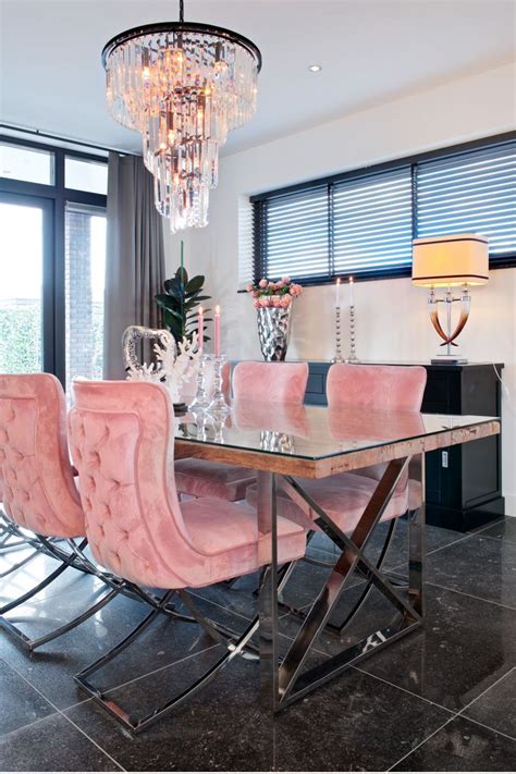 a dining room table with pink chairs and a chandelier