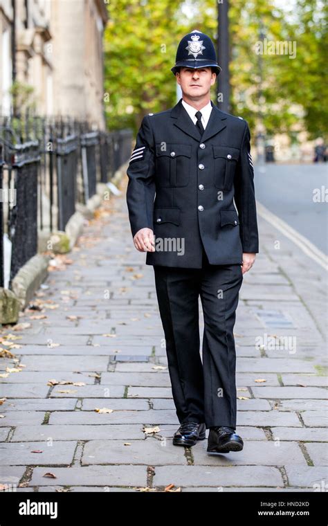 A smartly dressed English policeman in full uniform patrolling on his ...