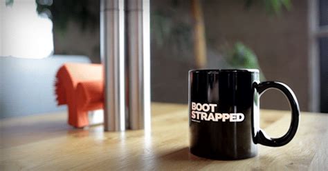 a black coffee mug sitting on top of a wooden table next to a red object