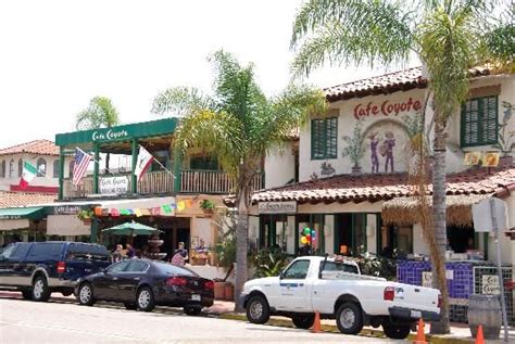 several cars parked on the side of a street in front of buildings with palm trees