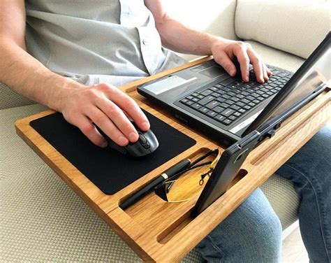 a man sitting on a couch using a laptop computer with his hands on the keyboard