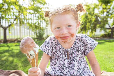 Caucasian girl with messy face eating ice cream cone - Stock Photo - Dissolve