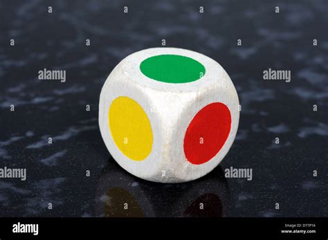 Standard six sided die with coloured spots against a black background ...